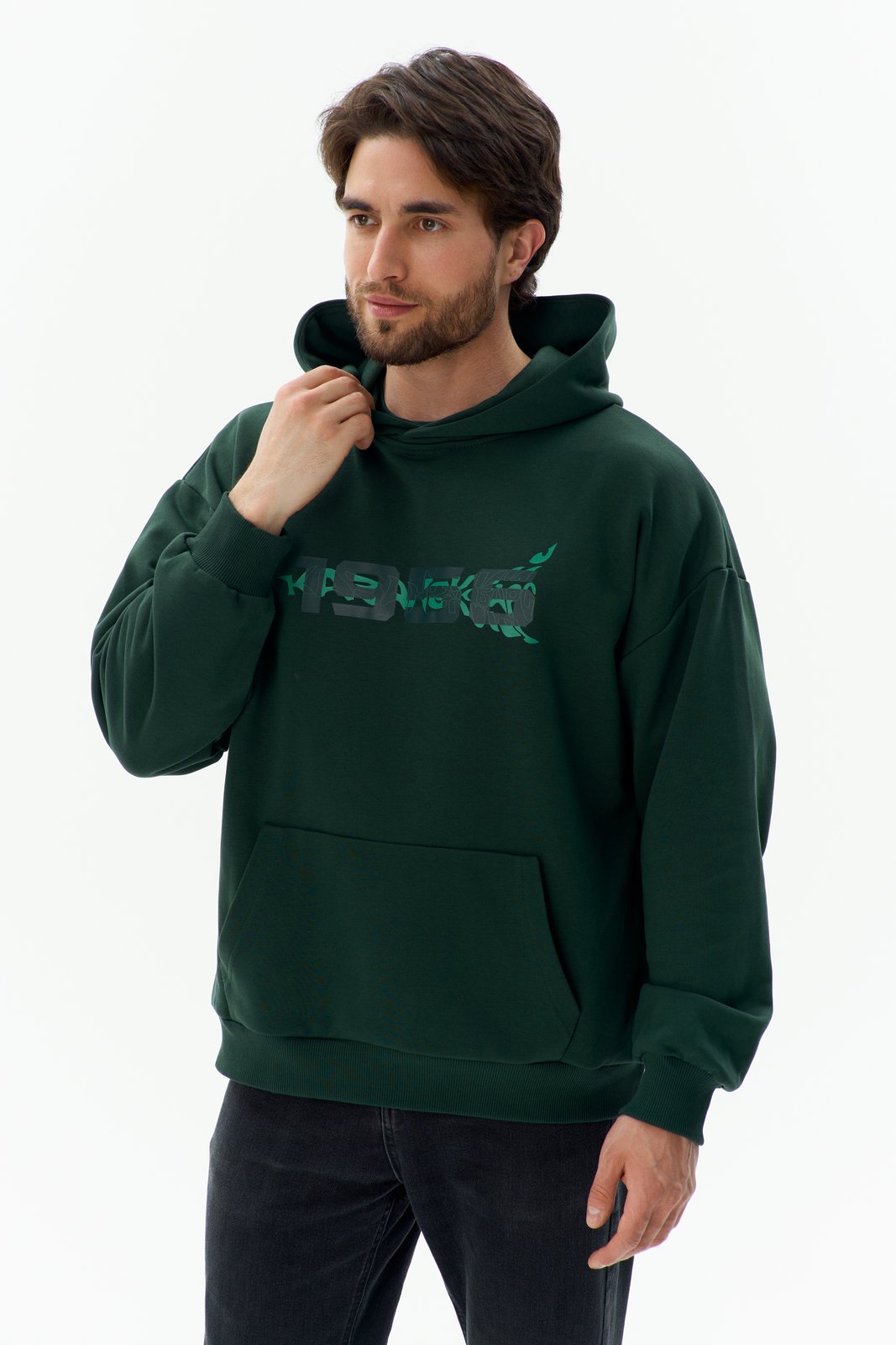 Ak Bars drop 2 — studio product shot of a man in a dark-green hoodie