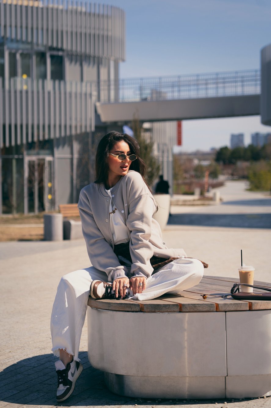 Ak Bars drop 3 — model seated on a bench in a grey bomber
