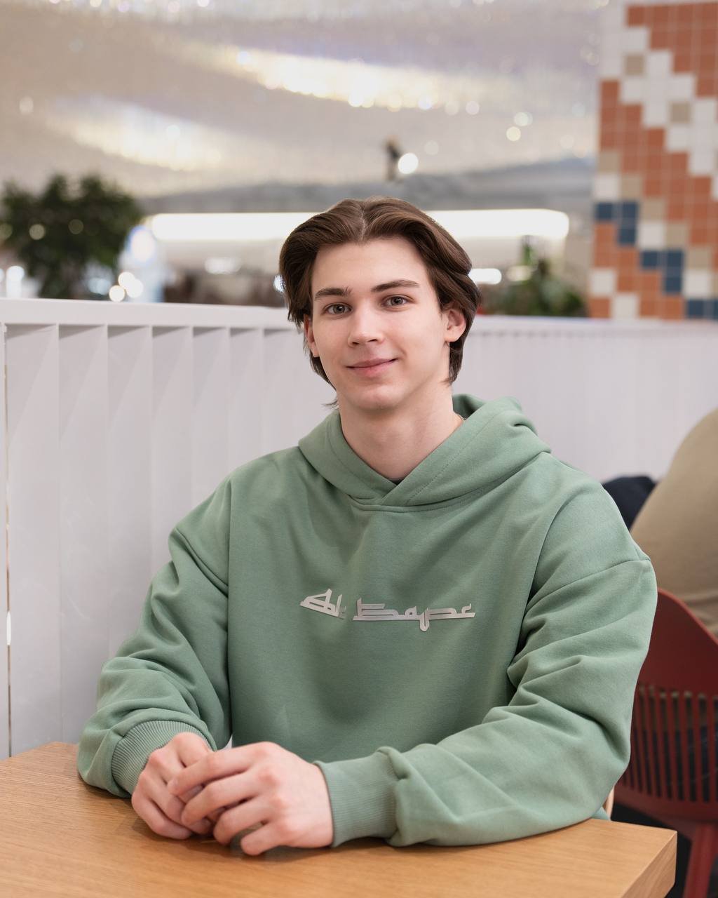 Ak Bars drop 3 — model at a table in a green hoodie