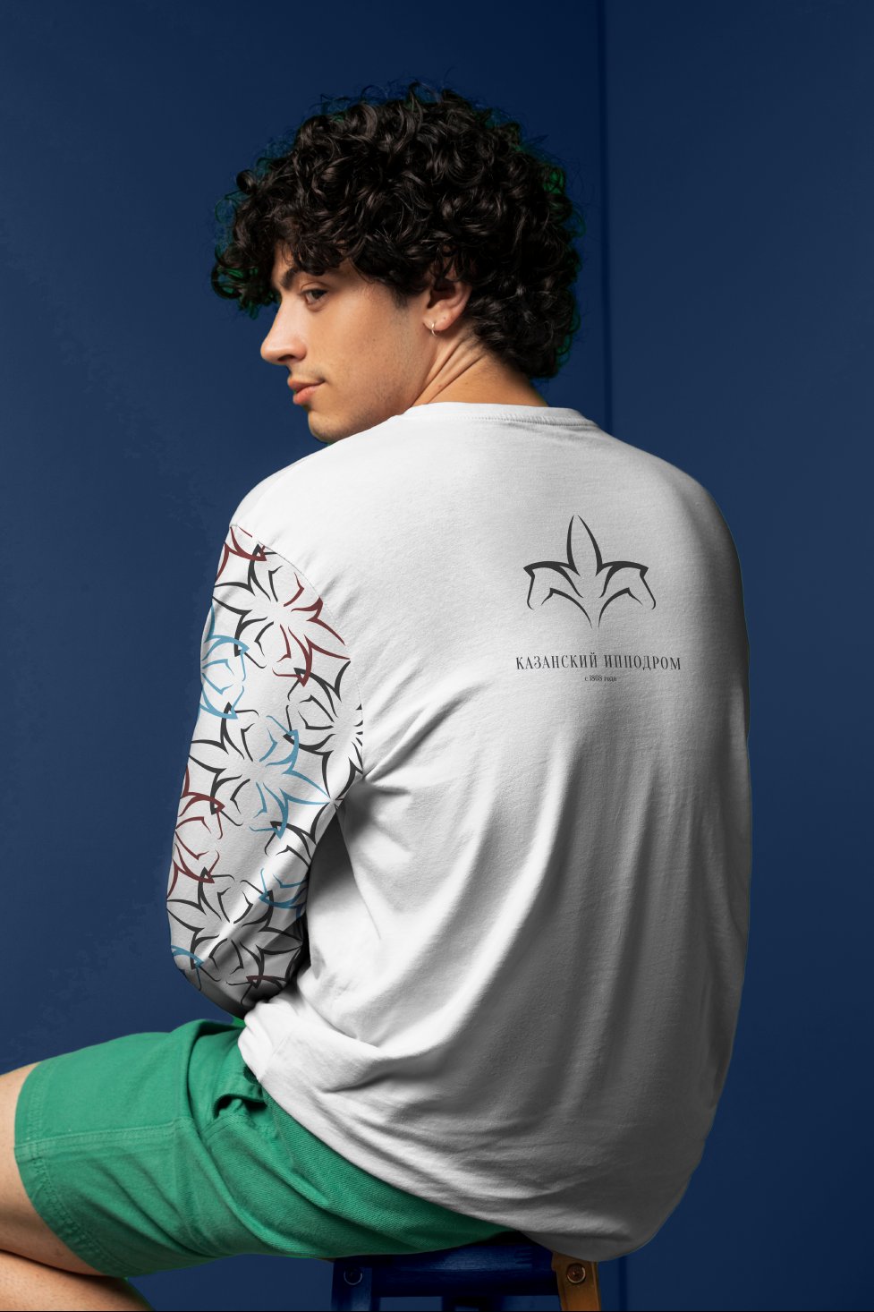 Back of a white long-sleeve with the tulip logo and wordmark, patterned sleeve, against deep blue