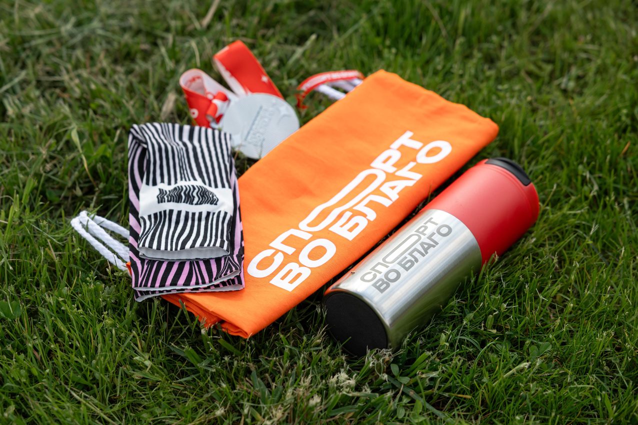 Event merchandise laid out on grass — branded towel, water bottle, socks and sneakers