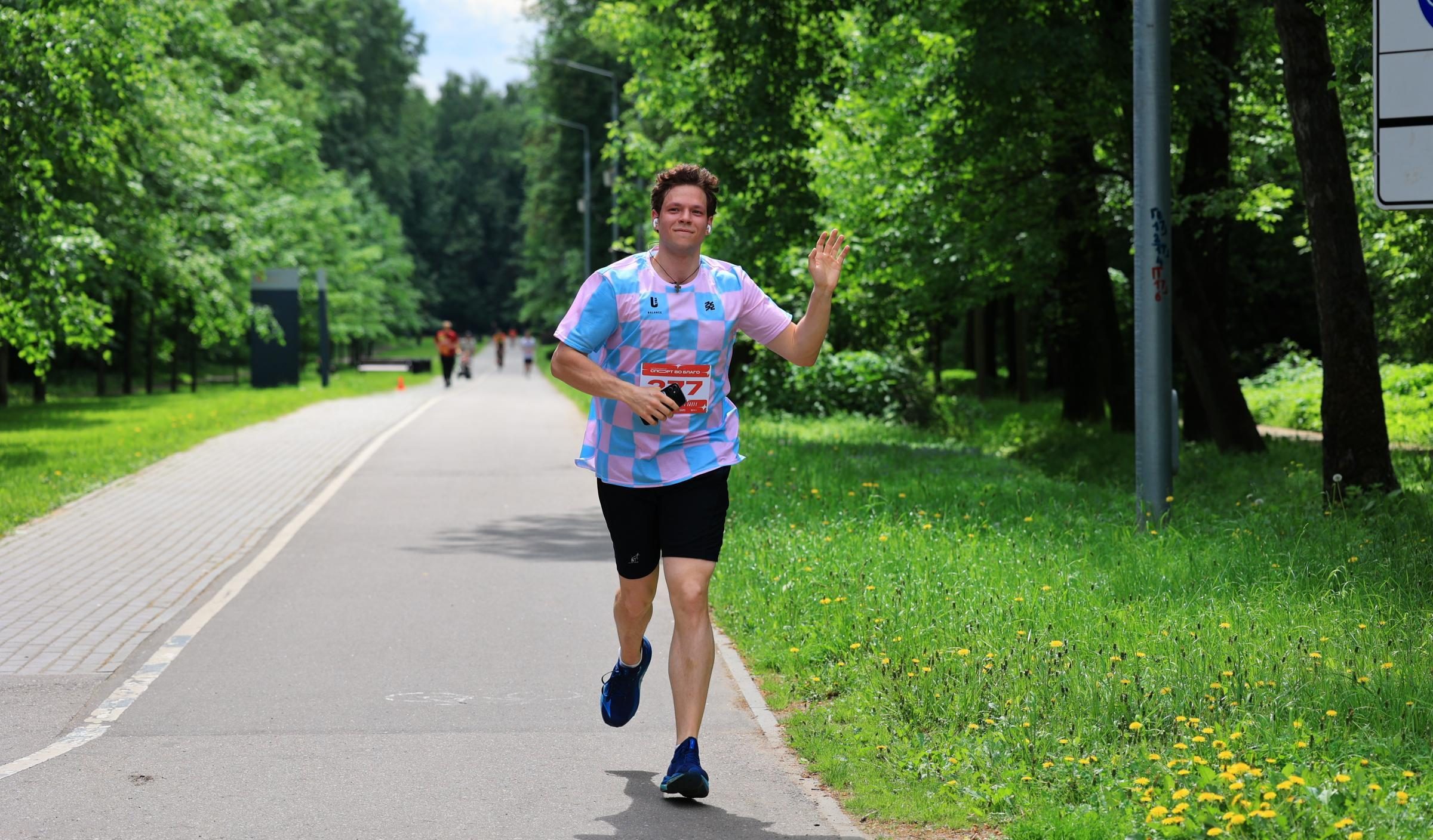 A runner waving to the camera on the park course during the race