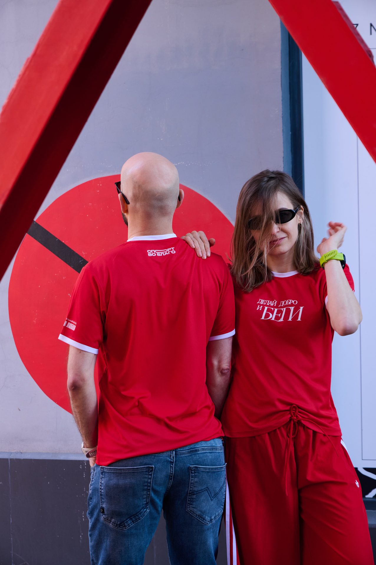A couple in red Sport for Good race kit in front of the event backdrop