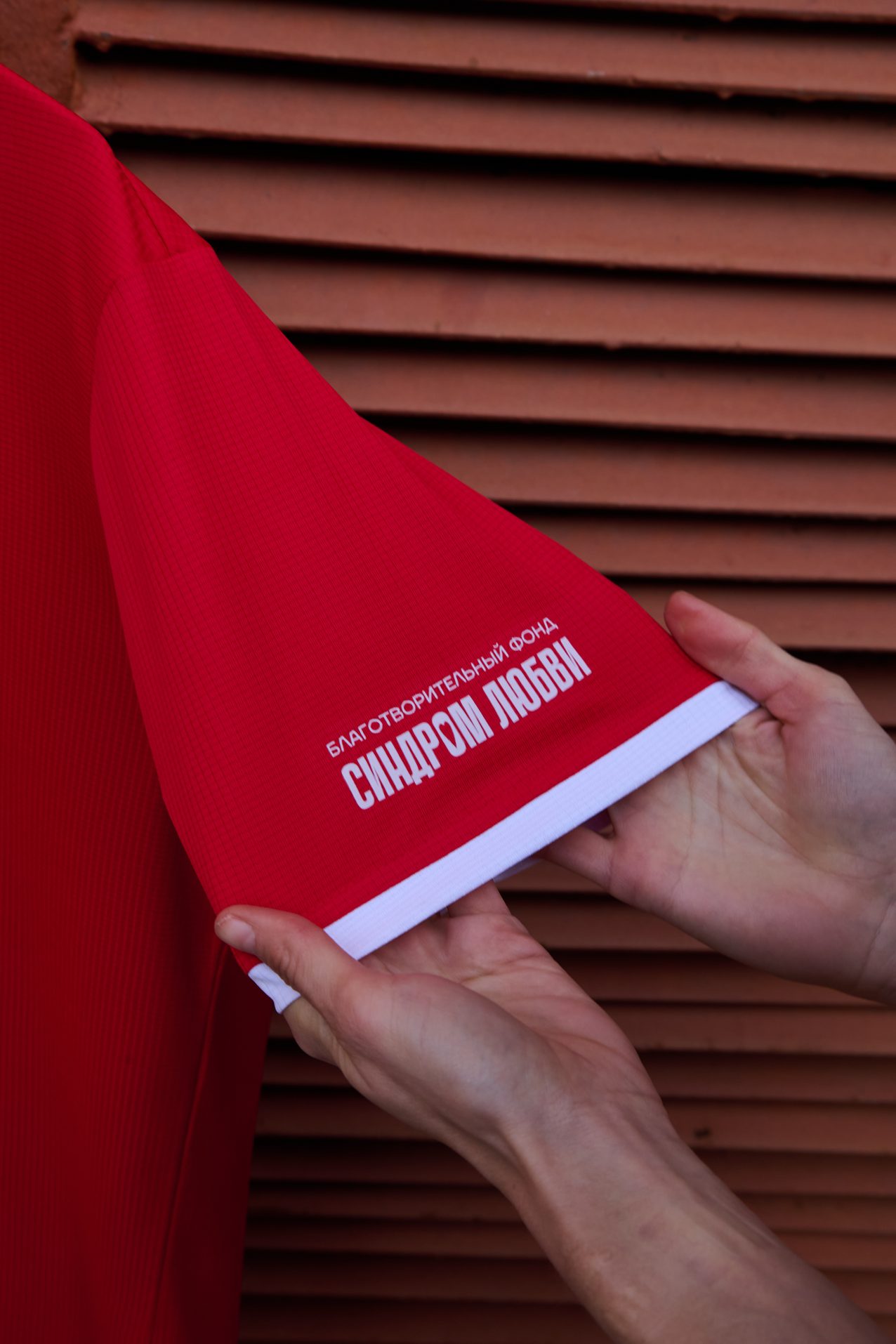 Hands folding a red race shirt against red slats