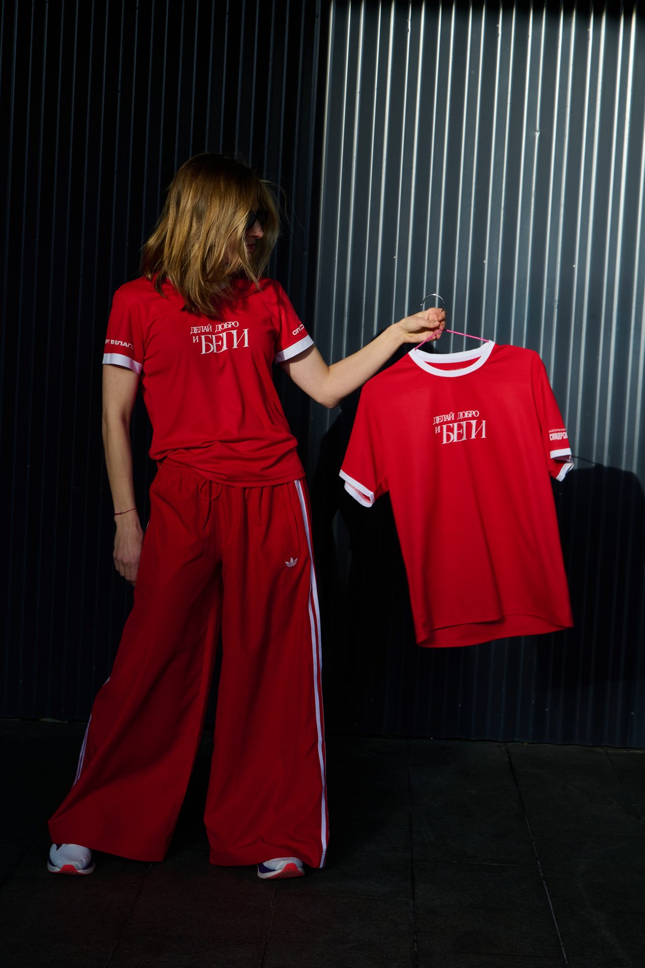 A runner in the red tracksuit holding up a race shirt on a hanger